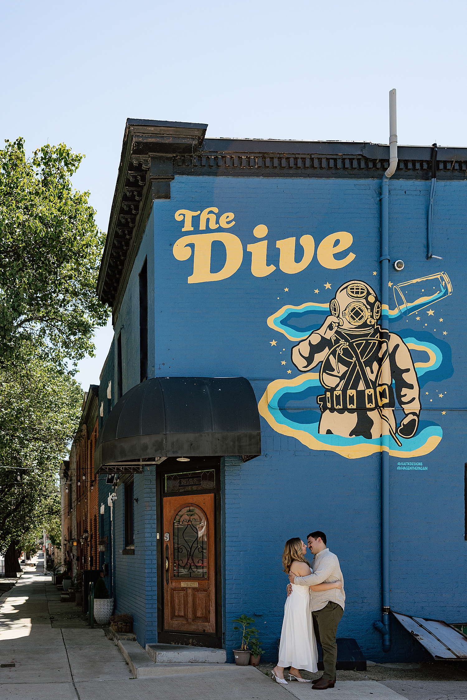 couple embrace under wall mural for The Dive at Boston engagement session