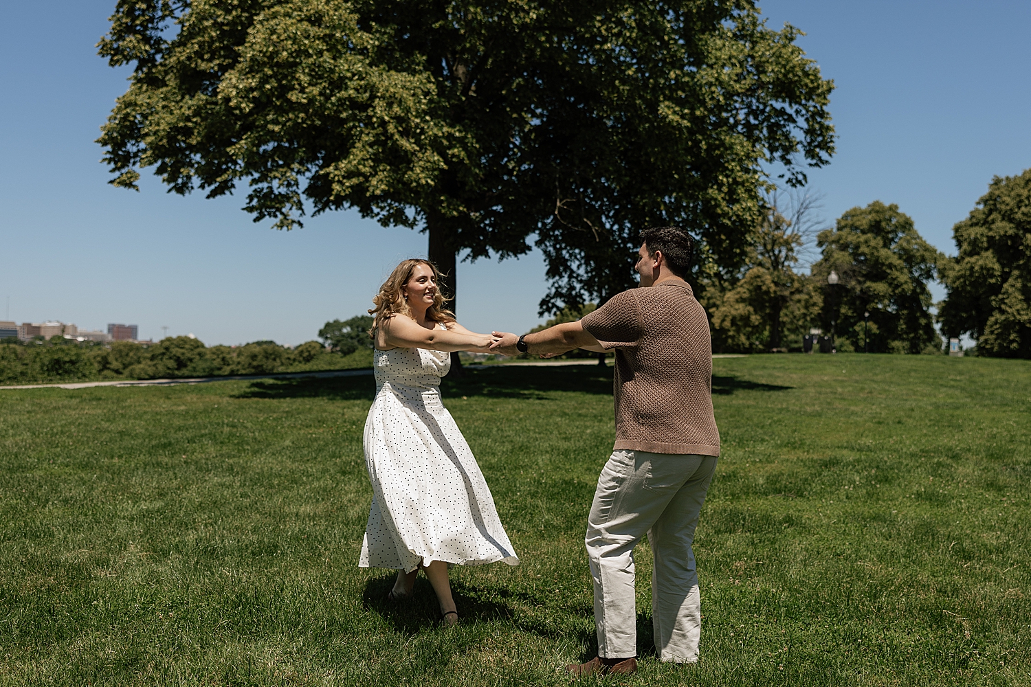 couple spin in a field in the bright sun for Boston engagement session