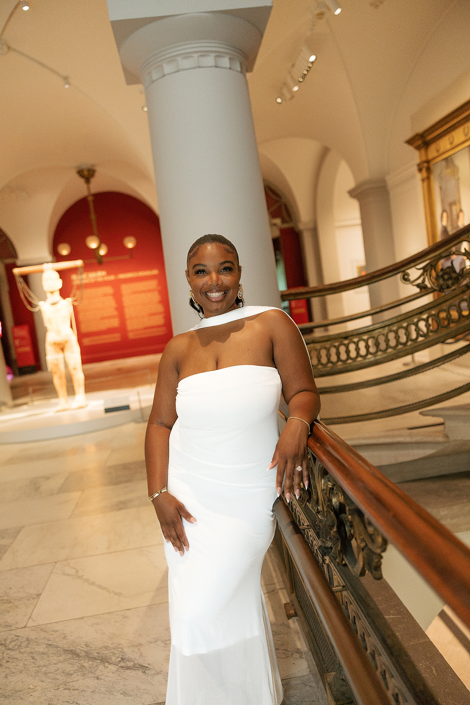 bride to be stands next to railing in gallery by Maryland wedding photographer