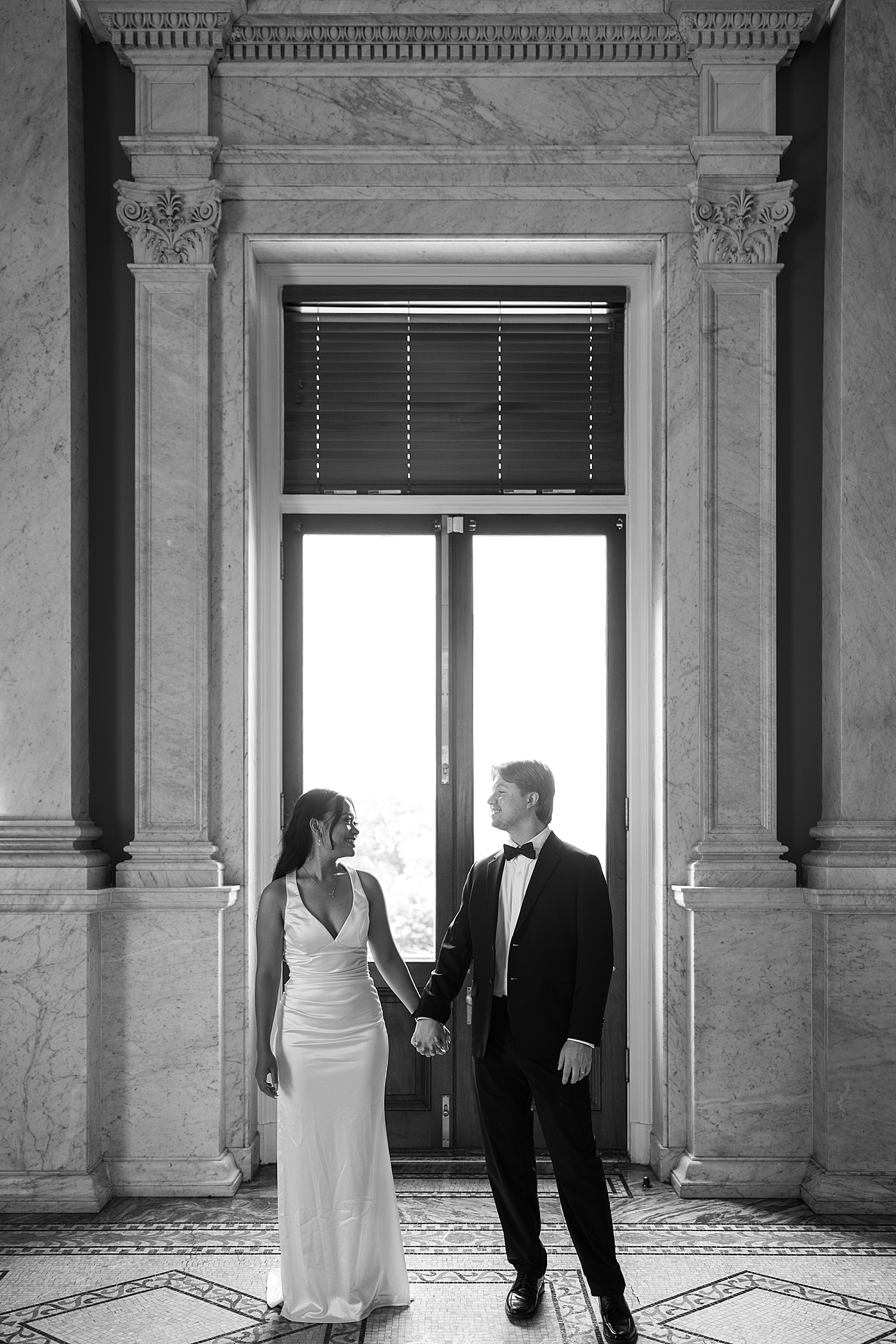 man and woman hold hands in front of old historic window at The Library of Congress