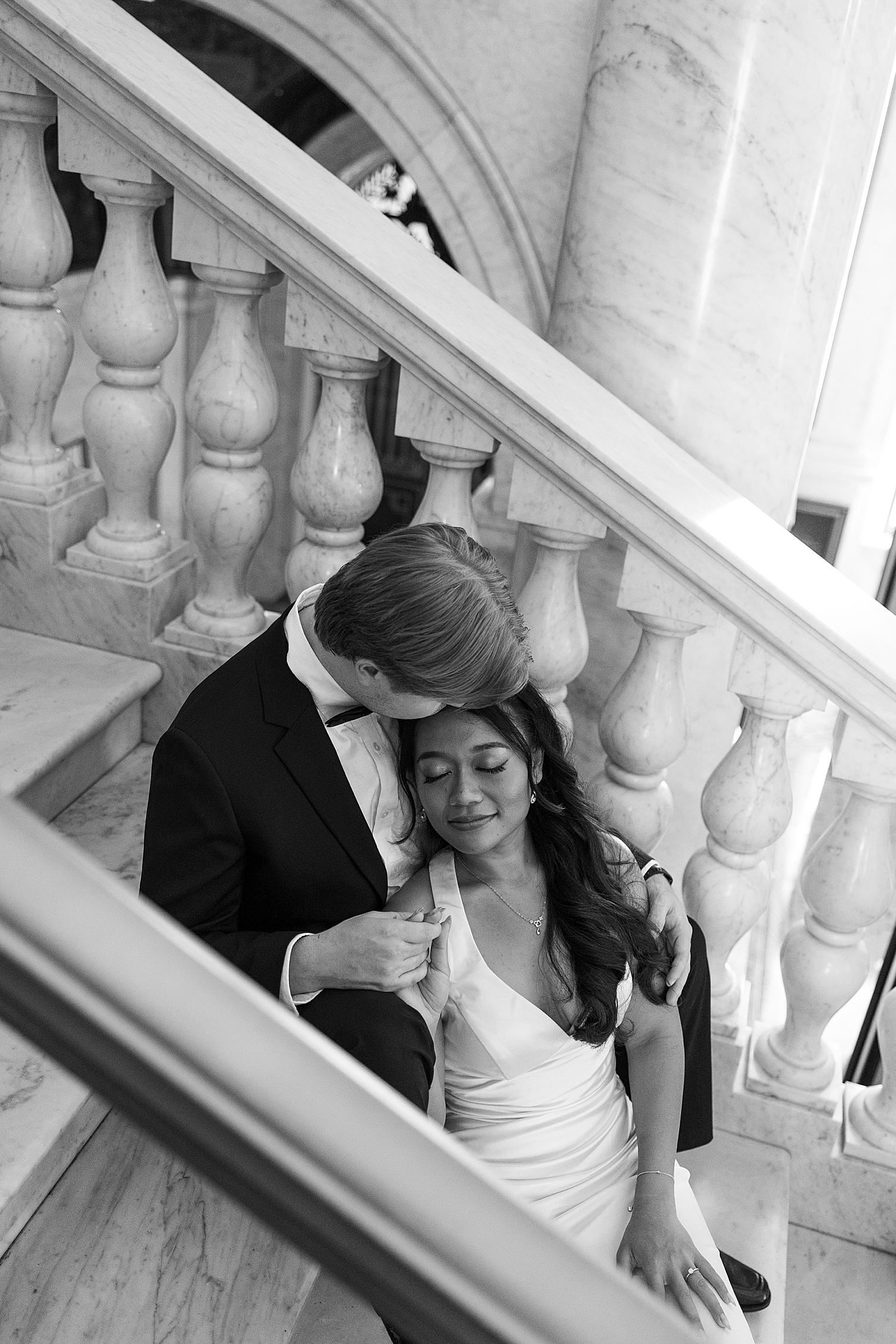 bride to be snuggles back against man on steps by Maryland wedding photographer
