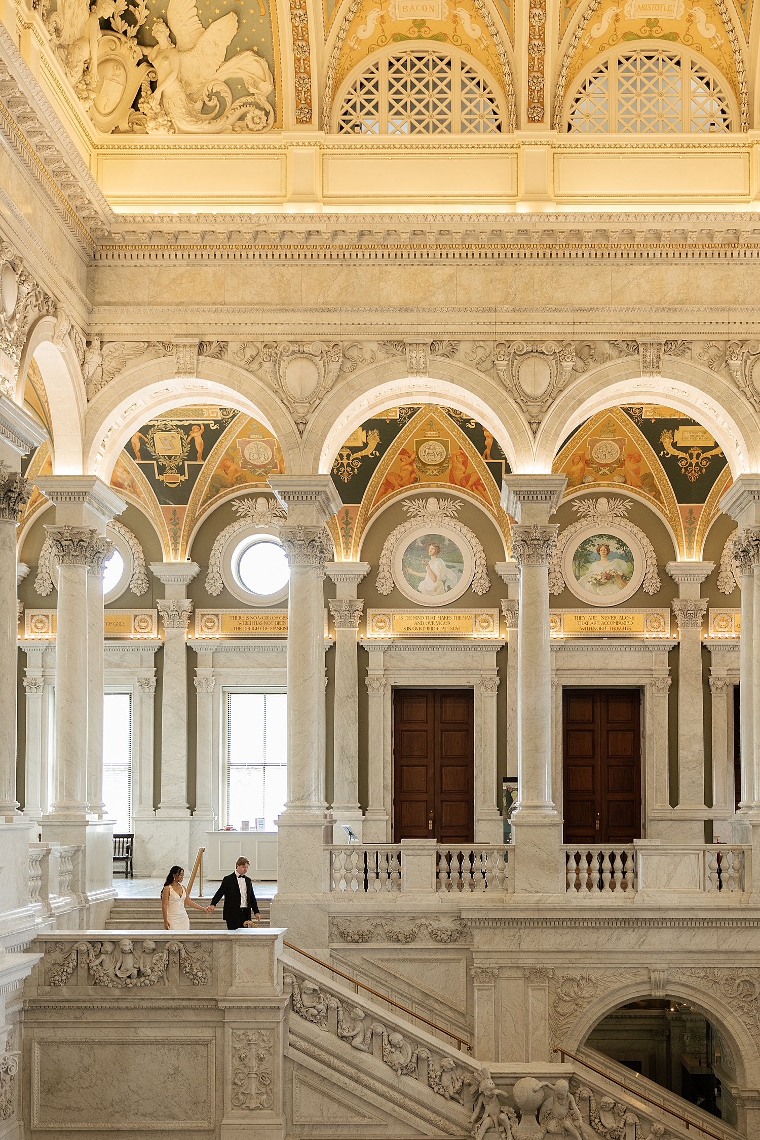man walks downstairs holding hands with his fiancé at The Library of Congress