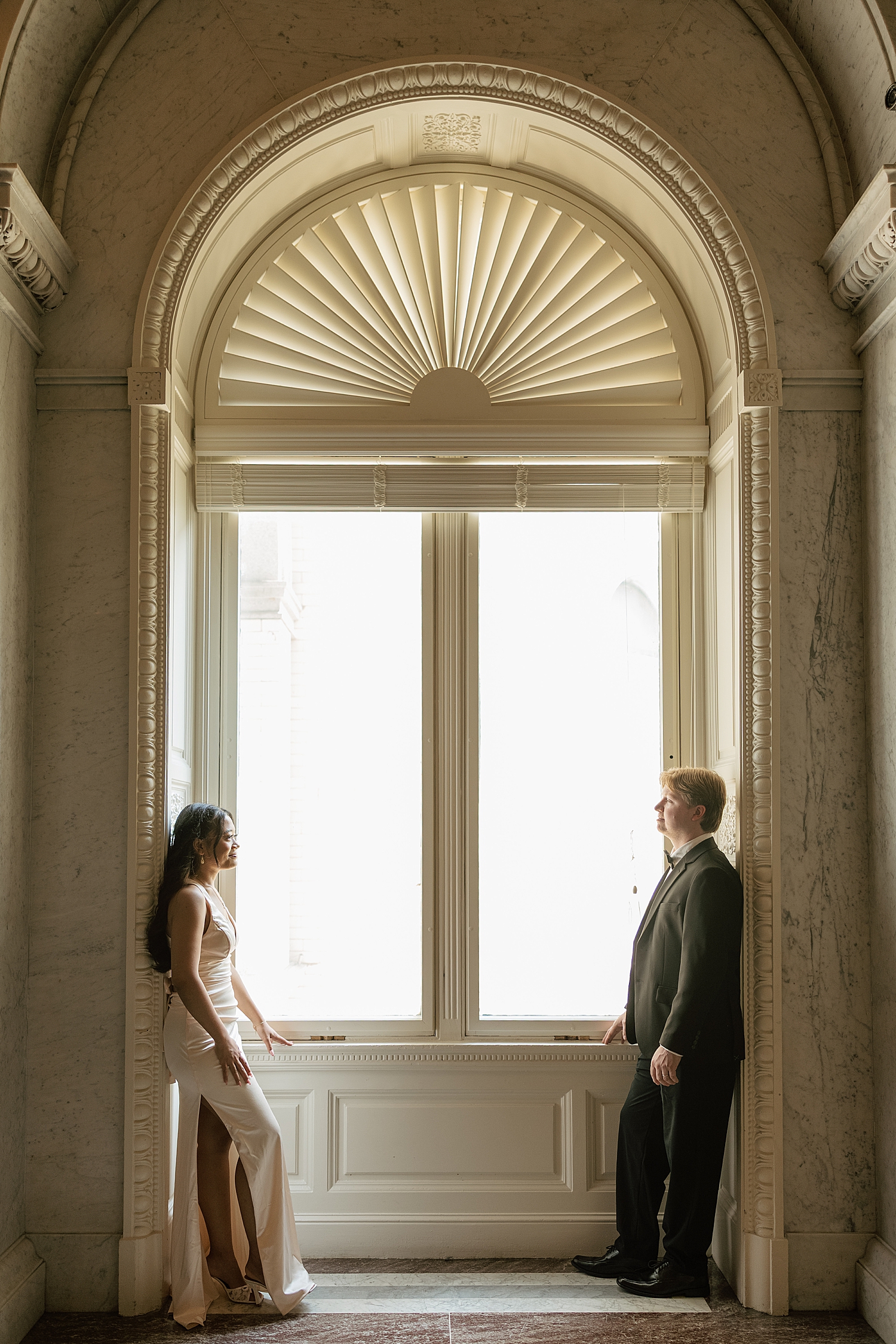 man and woman stand on opposite sides of big window at The Library of Congress