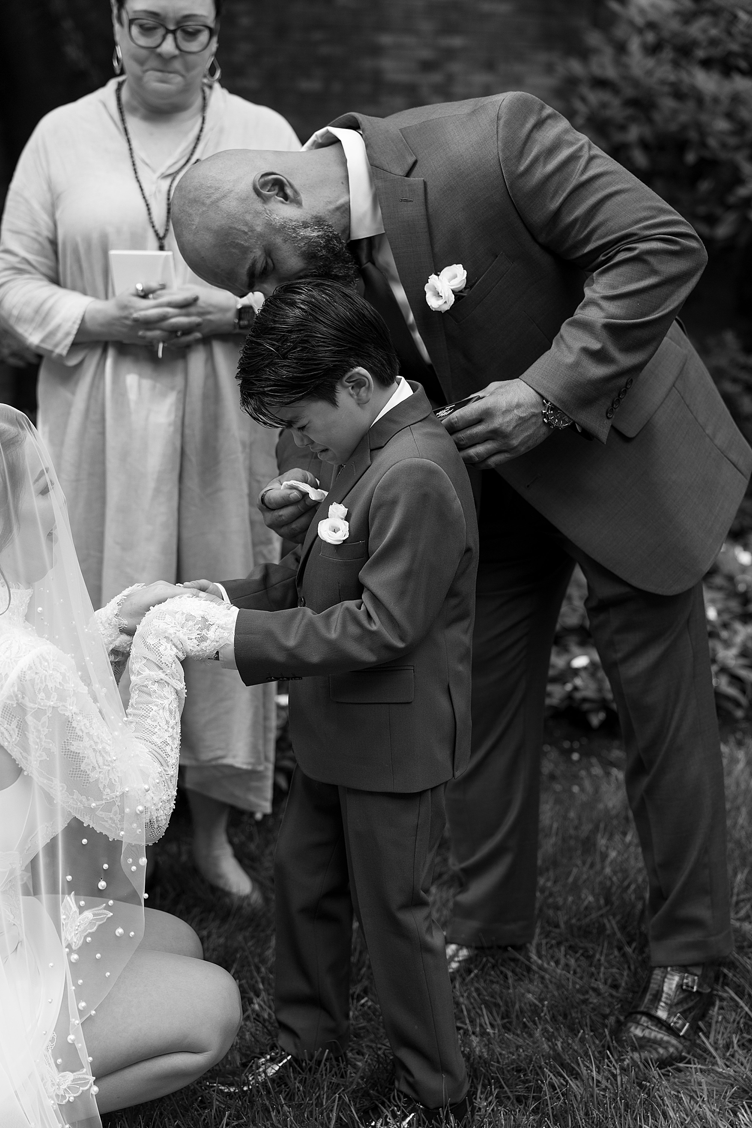 man leans down to comfort son crying during ceremony by Sharp Impressions Photography