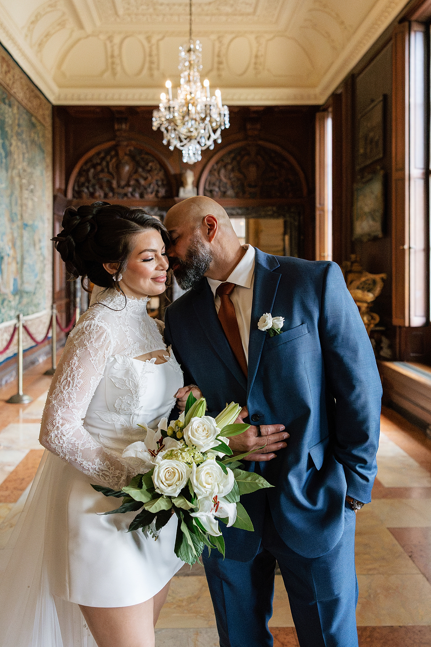 groom in blue leans in to kiss his bride indoors by Maryland wedding photographer