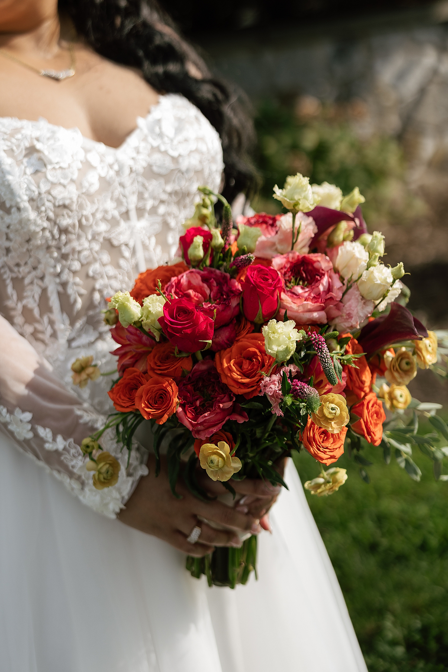 bride in lace dress holds reds flowers at The Mansion at Strathmore