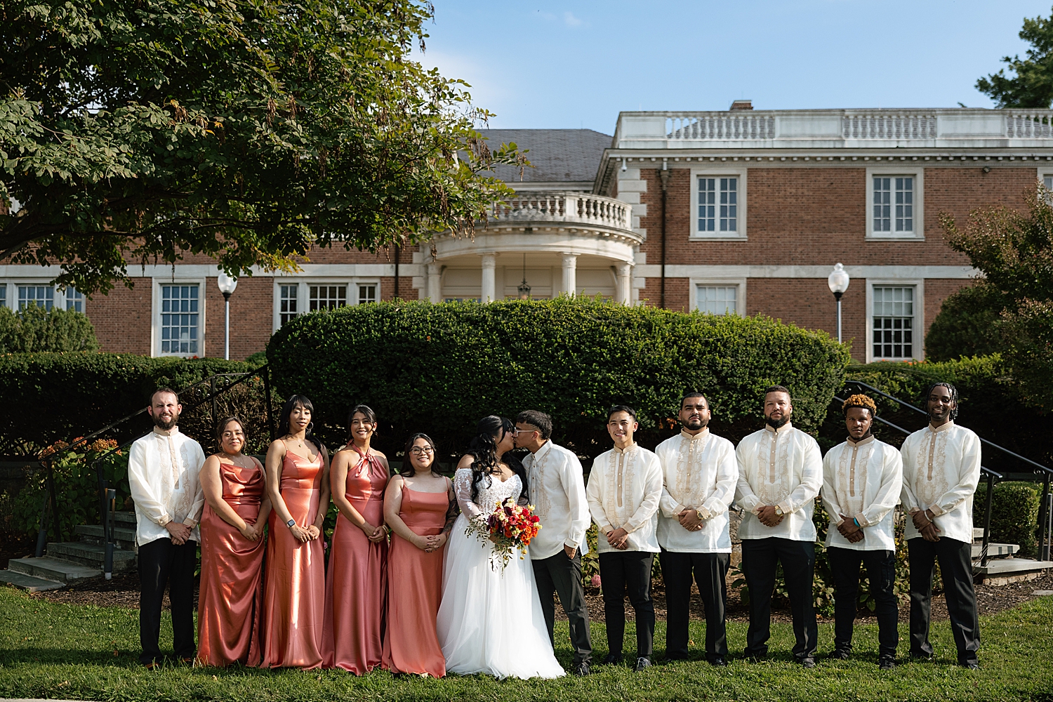 couple kiss surrounded by their groomsmen and bridesmaids by Maryland wedding photographer