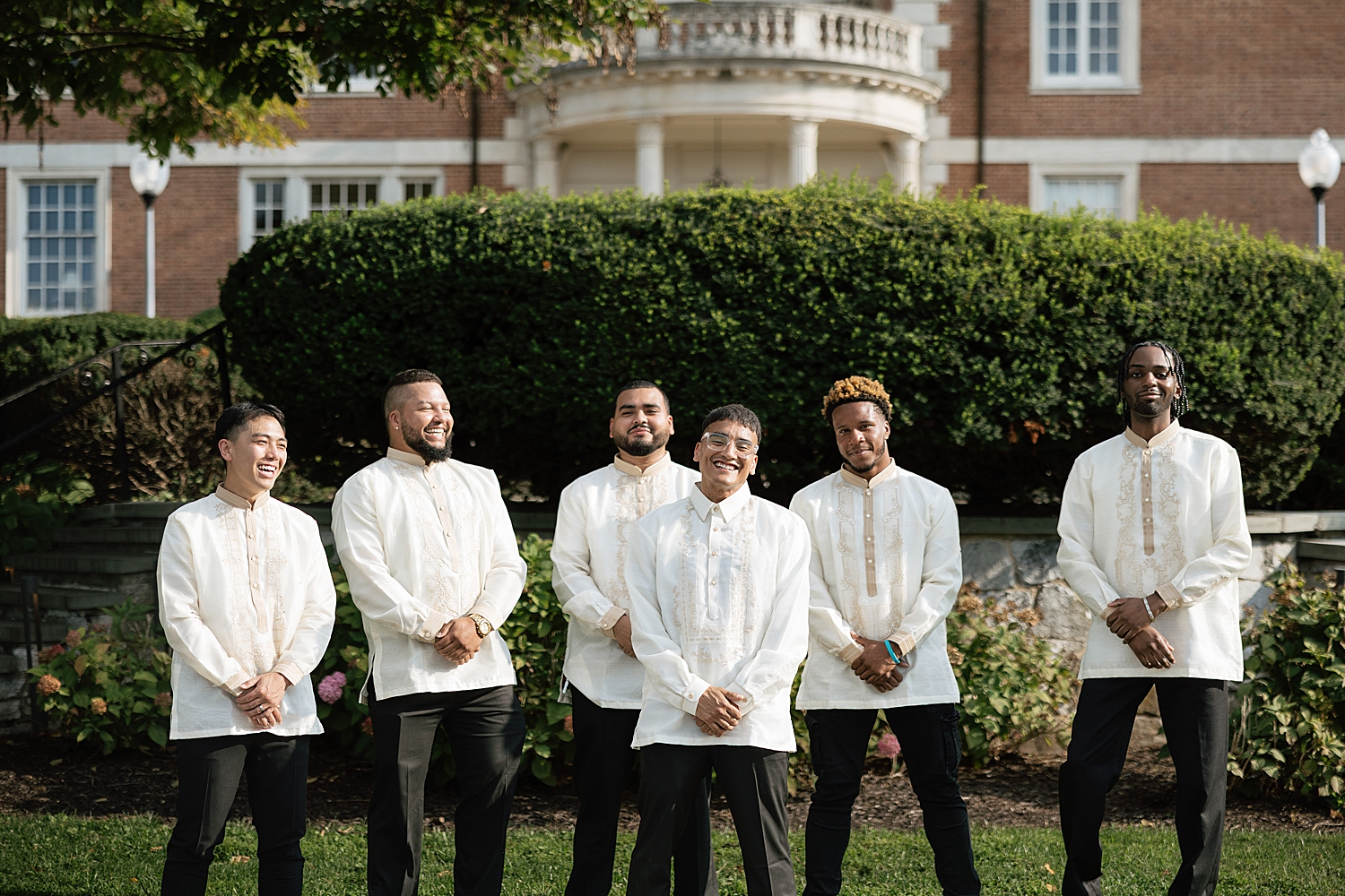 groomsmen stand behind groom in garden by Sharp Impressions Photography