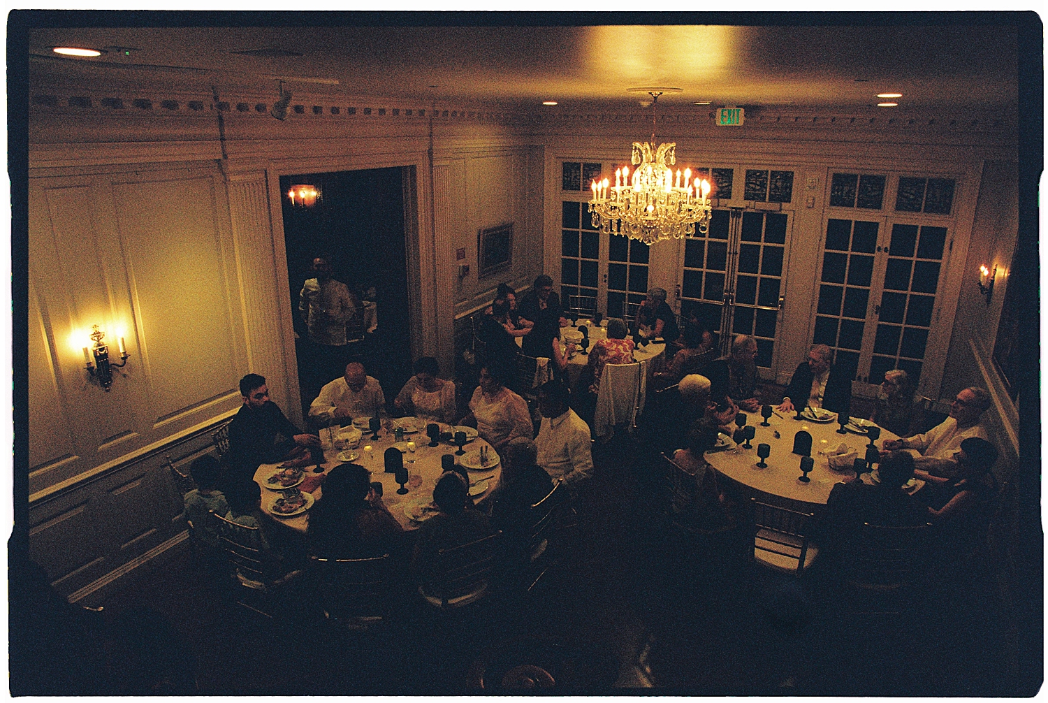 guests eat dinner at round tables in dimly lit room by Maryland wedding photographer