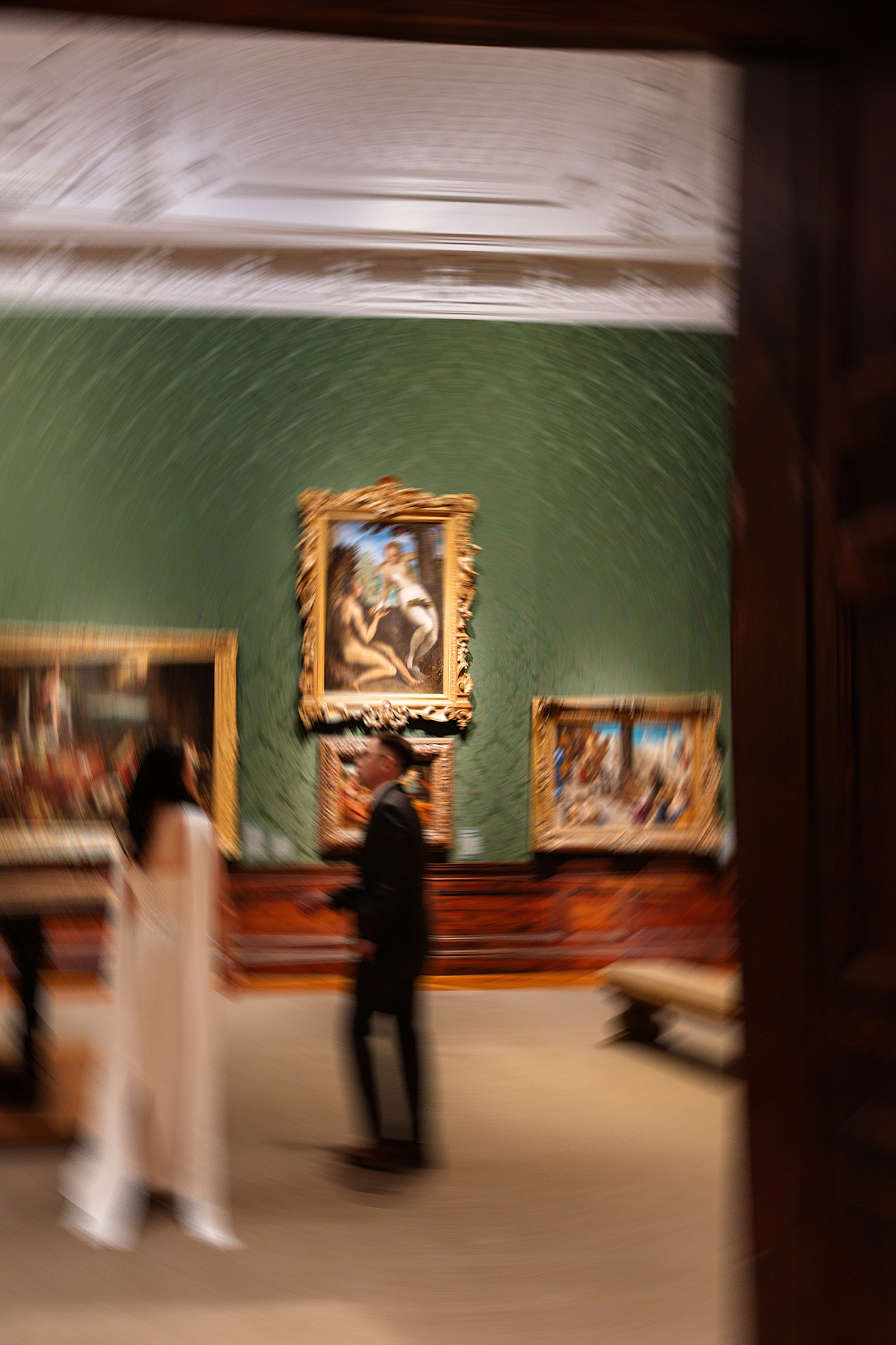 person in suit and woman in white dress in art gallery room by Sharp Impressions Photography