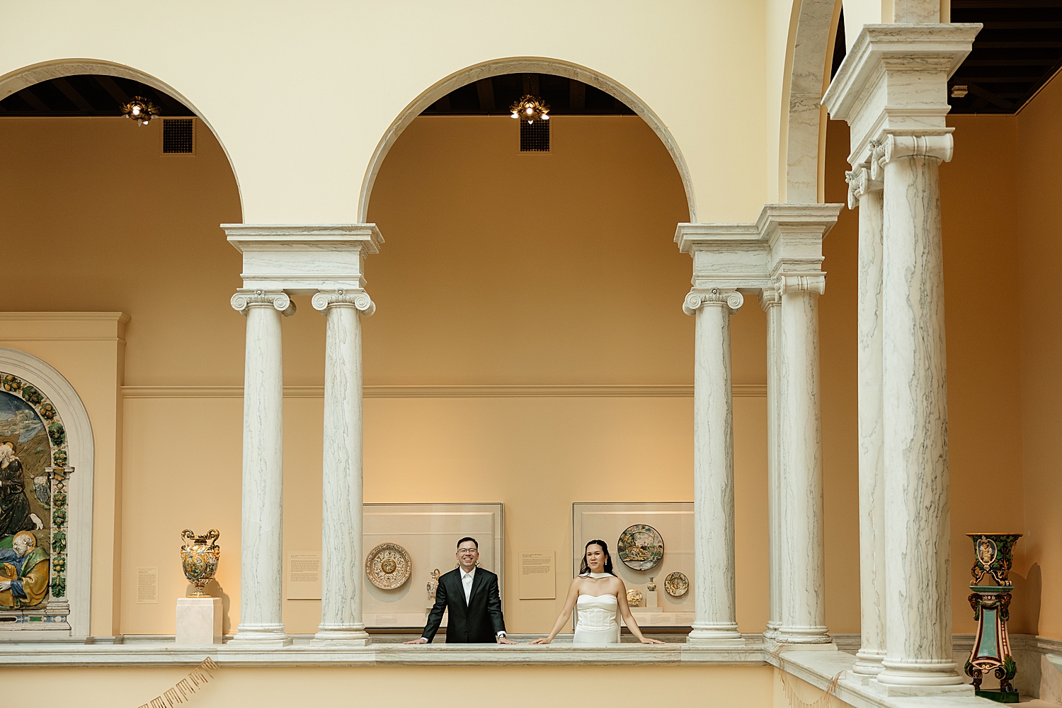 man and woman stand under large stone arch in gallery showing Engagement Session Locations in Baltimore