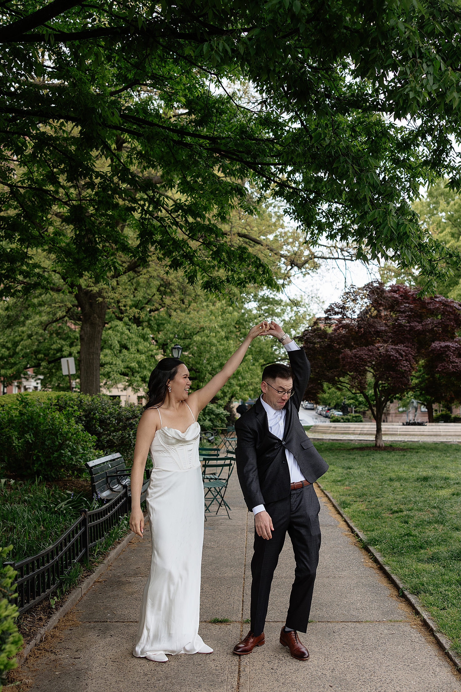woman in white dress spins her groom in park showing Engagement Session Locations in Baltimore